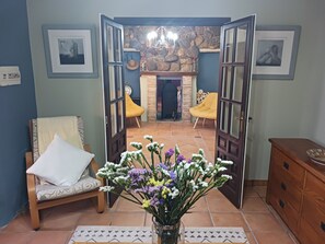 An open doorway leading to a living area with a stone fireplace, a yellow armchair, and a wooden cabinet.