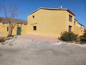 A yellow building with a green door, a satellite dish, and a small window.