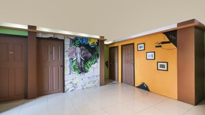 Um corredor com portas castanhas, um mural de um elefante e quadros nas paredes.