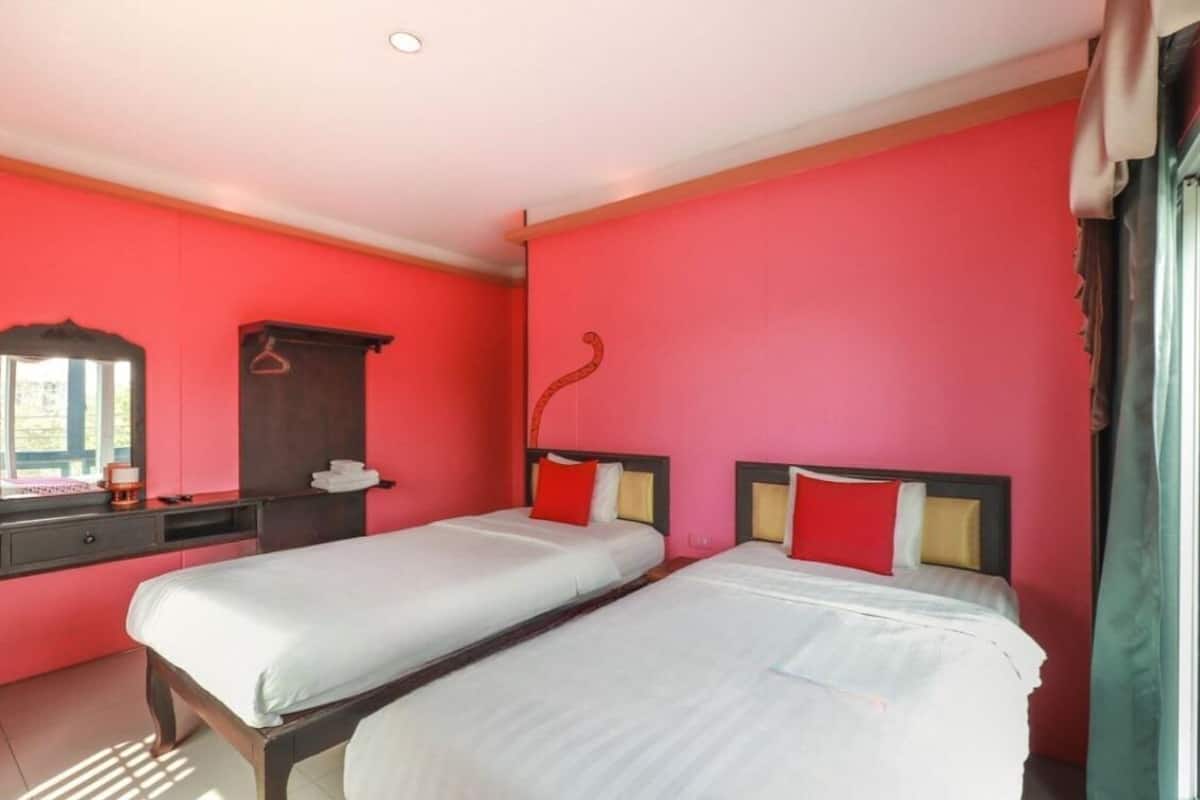 A hotel room with two beds, a dresser, and a mirror.