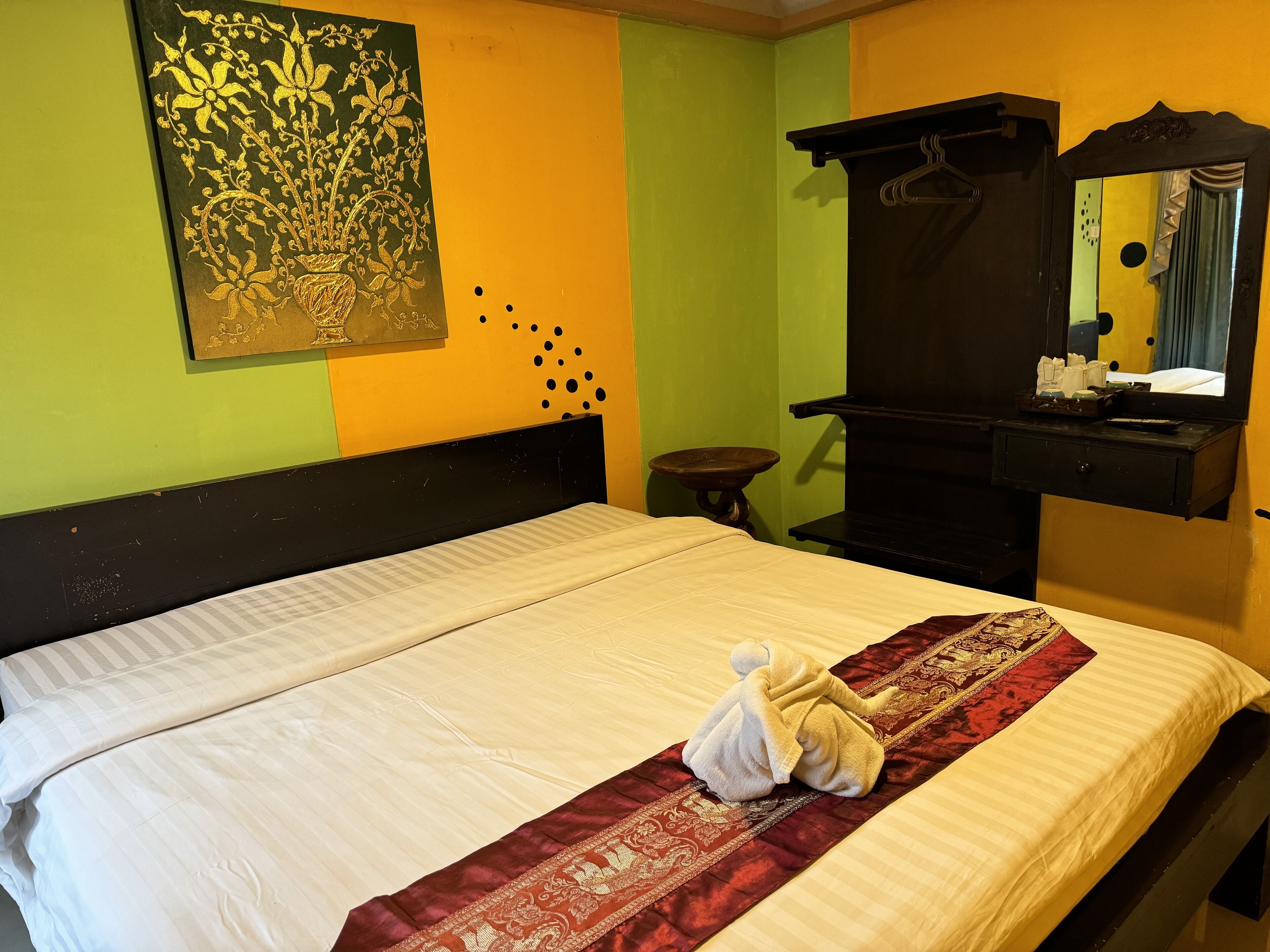 A neatly made bed with a white comforter and a red and gold decorative runner.