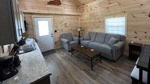 A cozy cabin interior with a wooden ceiling, a sofa set, a coffee table, and a kitchen area with a countertop and appliances. - Lillie's Pad -Cozy 2-bedroom cabin- 20 miles from Natural Bridge in Beattyville. (Beattyville)