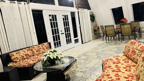 Une pièce comprenant un ensemble de canapés, une table avec un plateau en verre et un coin repas avec des chaises.
