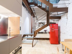 A modern kitchen with stainless steel appliances, a wooden door, and a red refrigerator.