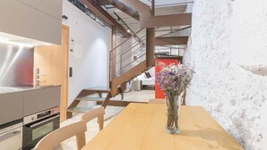 Une cuisine moderne équipée d’appareils électroménagers en acier inoxydable, une table à manger en bois et un vase rempli de fleurs.