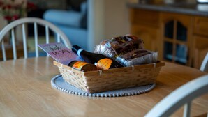 A wicker basket on a wooden table with a bottle, a loaf of bread, and a card. - Ben View located in Teslaig, Fort Willam (Treslaig)