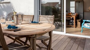 Un espace de restauration en plein air avec une table et des chaises en bois, une bouteille de vin et une carafe.