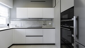 Una cocina moderna con armarios blancos, una campana extractora de acero inoxidable y un horno empotrado.
