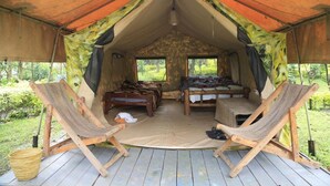A tent with two beds and two wooden chairs, set on a wooden deck with a view of greenery. - Room in B&B - Red Rocks Rwanda - Safari Tent Twin (Nkotsi)