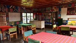 A room with multiple beds and tables, each with colorful patterned tablecloths. - Room in B&B - Red Rocks Rwanda - Safari Tent Twin (Nkotsi)