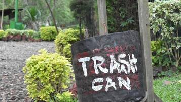 Un letrero que dice 'TRASH CAN' en un jardín.