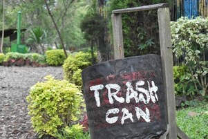 Un letrero que dice 'TRASH CAN' en un jardín.