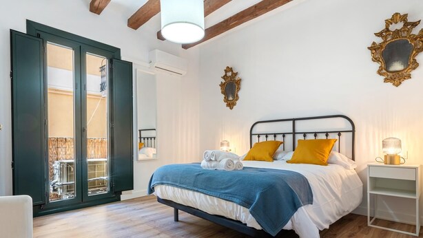 Ein Schlafzimmer mit einem Bett, einem Nachttisch, einem Spiegel und einer Balkontür.