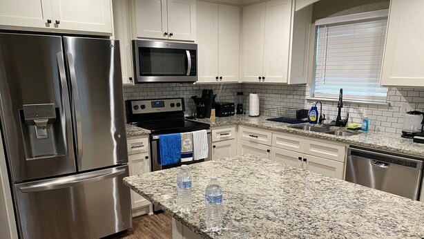 A modern kitchen with stainless steel appliances, granite countertops, and white cabinetry. - Charming 3BR Retreat Near Tyler Airport & Downtown (Tyler)