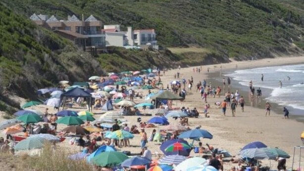 A beach with umbrellas and people, a building with a sloped roof, and a hillside. - 87 Sand Street - Buffels bay (Buffels Bay)