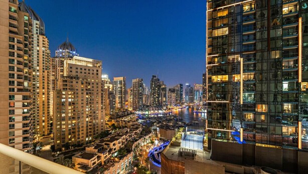 A nighttime cityscape with high-rise buildings, a river, and illuminated bridges.