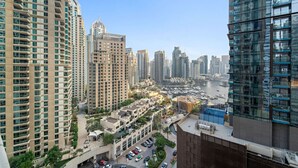A high-rise residential building with multiple balconies, a marina with boats, and a clear view of the city skyline.