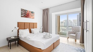A modern hotel room with a large bed, a nightstand, a chair, and a city view through the balcony.