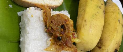A plate of food with white rice, fried items, and bananas on a banana leaf.