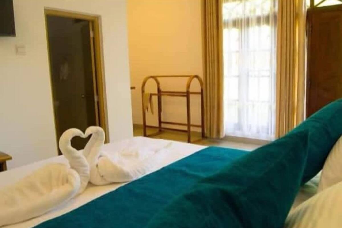 Quarto de hotel com cama, janela com cortinas e porta.