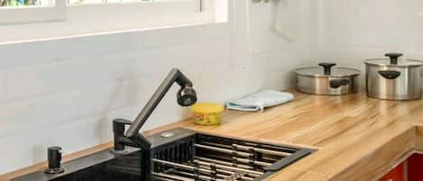 Una cocina moderna con un lavamanos negro, encimera de madera y armarios rojos.