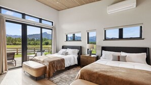 A modern bedroom with two beds, a large window, and an air conditioning unit.