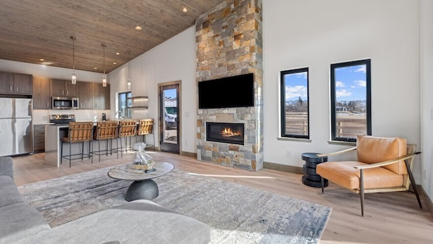 Una sala de estar moderna con chimenea de piedra, una zona de bar y un televisor grande montado en la pared.