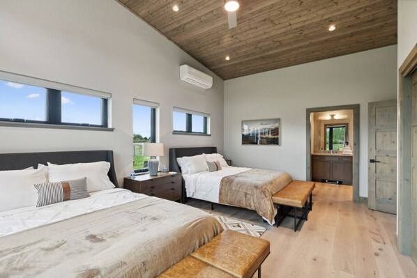 Une chambre avec deux lits, un plafond en bois et une vue sur l’extérieur.