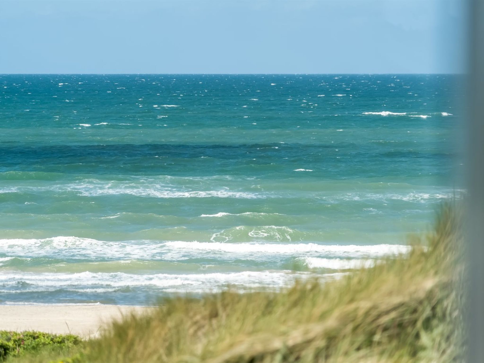 Blick auf den Ozean mit Wellen und einem Sandstrand.