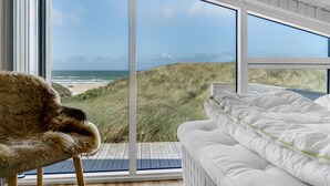 Una camera da letto con un'ampia finestra vista spiaggia e dune.