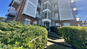 Un edificio residencial de varios pisos con balcones, fachada de ladrillo y cielo despejado.