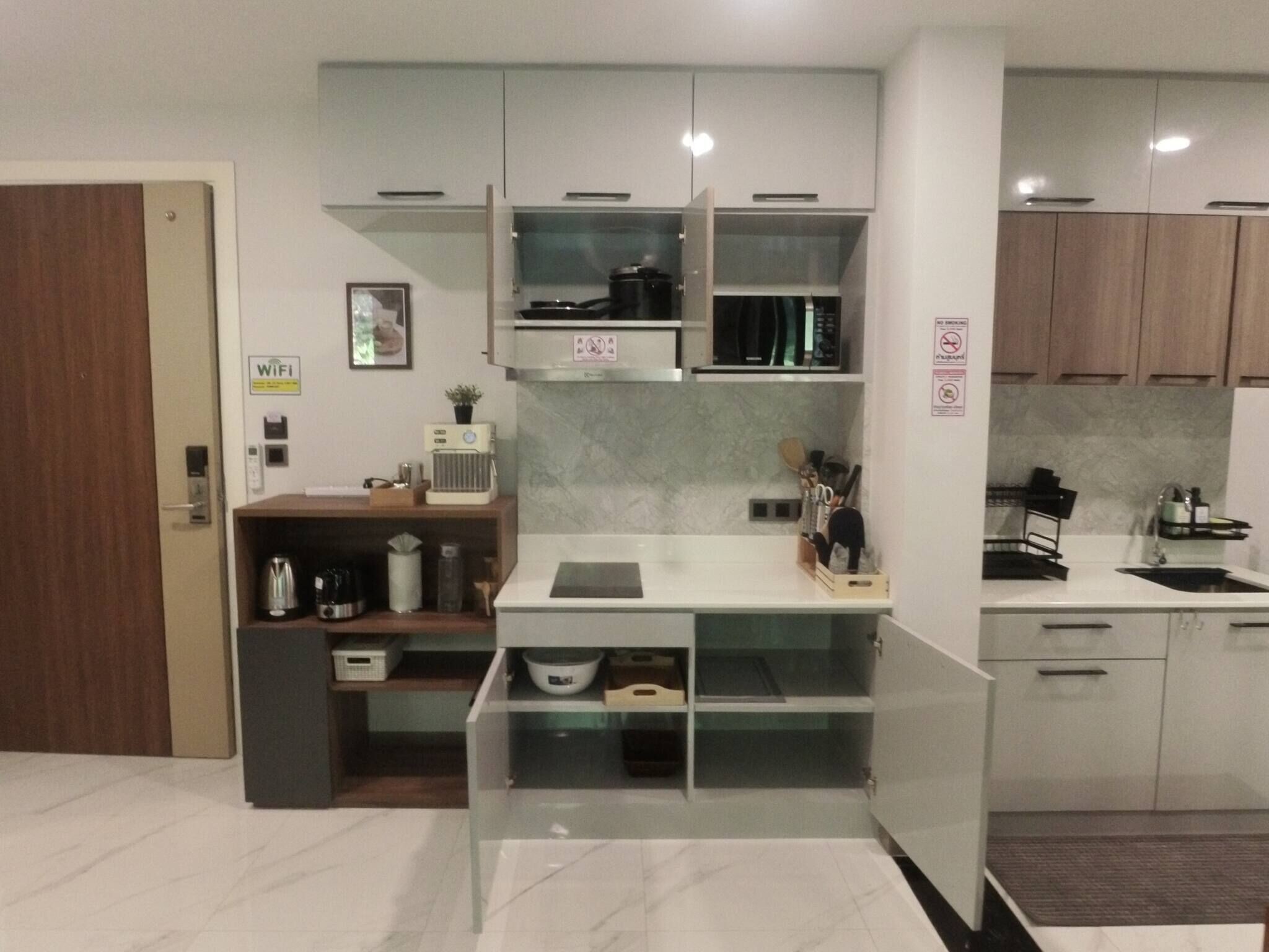 A modern kitchen with white cabinets, a built-in microwave, and a coffee machine.