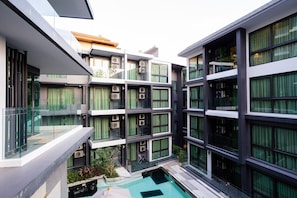 A multi-story building with balconies, large windows, and a central courtyard with a pool.