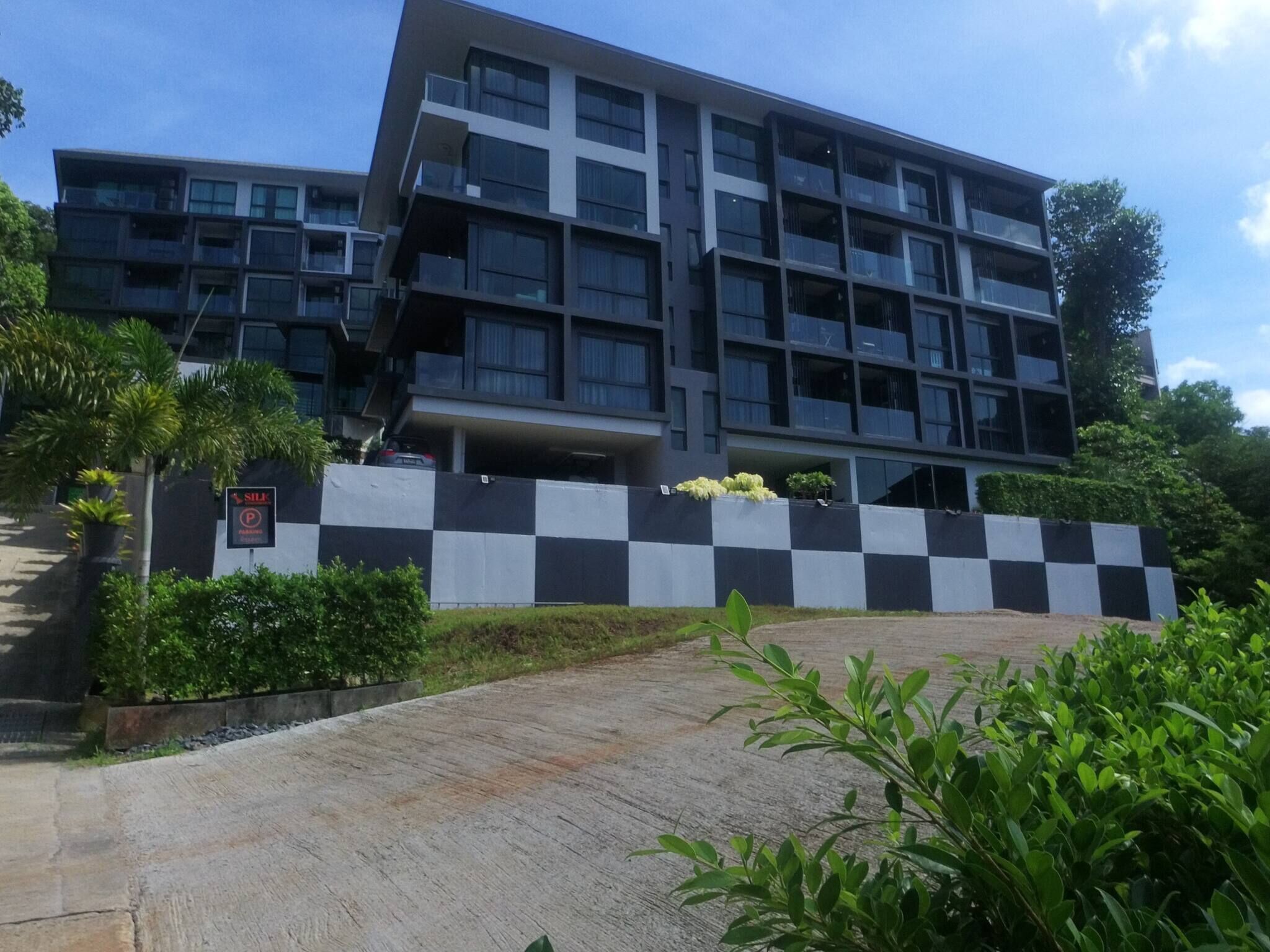 A modern multi-story building with a checkered wall and a sign indicating a parking area.
