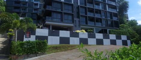 A modern multi-story building with a checkered wall and a sign indicating a parking area.