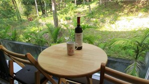 Enjoy a serene moment on the balcony with a glass railing, overlooking a lush garden.