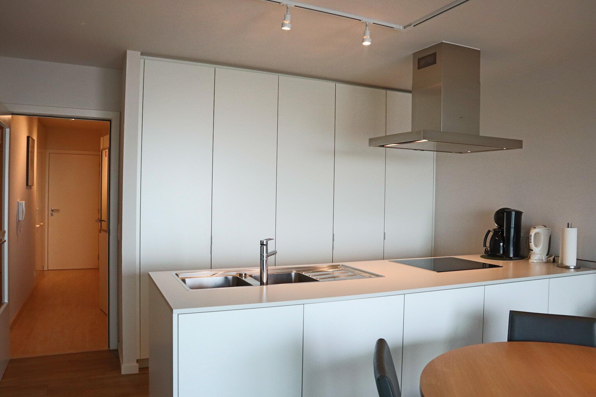 A modern kitchen with a central island, stainless steel appliances, and a built-in oven hood.