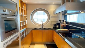 A compact kitchen with a built-in oven, a window, and a sink.