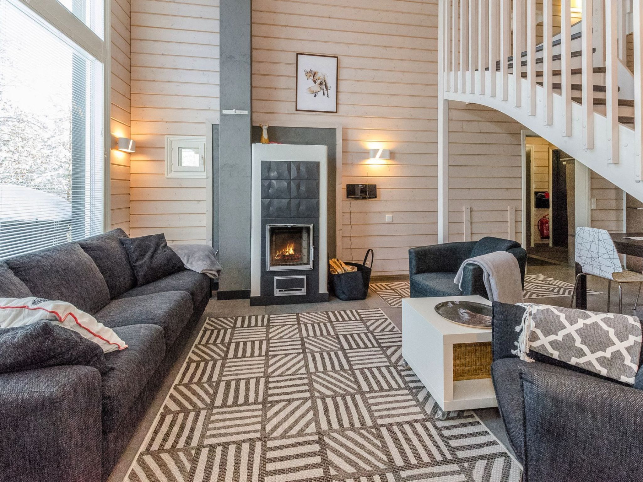 Un salon avec une cheminée, un canapé, une table basse et un escalier.