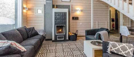 Una sala de estar con chimenea, un sofá, una mesa de centro y una escalera.
