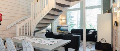 Un interior moderno con una escalera de caracol, una zona de comedor con mesa y sillas, y una sala de estar con sofá y televisión.