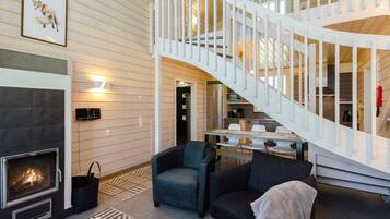 A modern interior with a fireplace, a staircase, and a dining area.