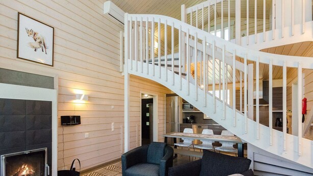 A modern interior with a fireplace, a staircase, and a dining area.