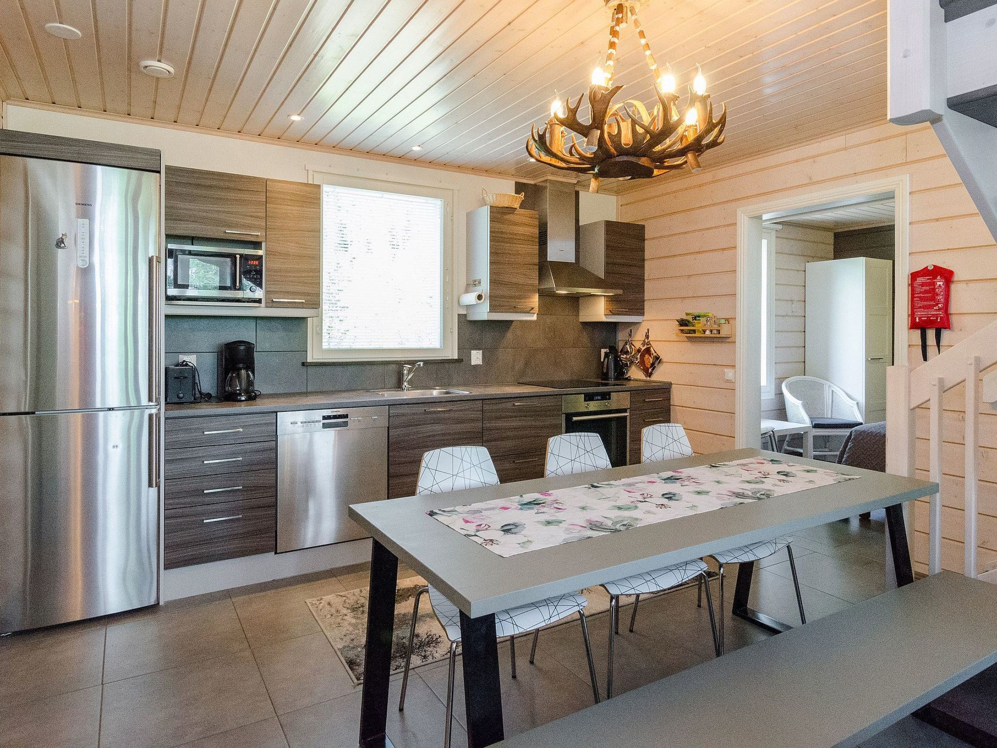Una cocina moderna con electrodomésticos de acero inoxidable, un comedor con mesa y sillas, y una araña.
