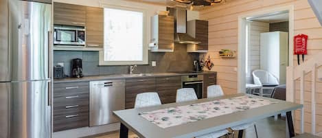 Una cocina moderna con electrodomésticos de acero inoxidable, un comedor con mesa y sillas, y una araña.