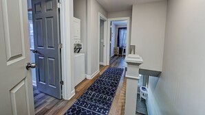 A hallway with a patterned rug, a door, and a small table with a vase. - Chic Spacious Downtown Retreat (Indianapolis)