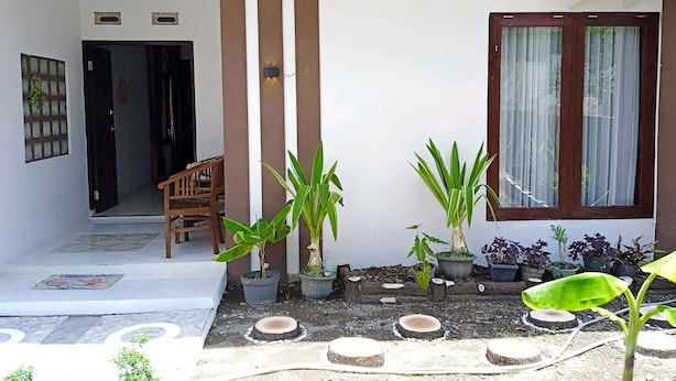 Ein modernes Haus mit Terrasse, das mit Blumentöpfen und einer hölzernen Bank ausgestattet ist.