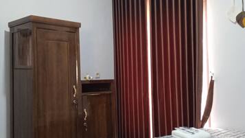 A bedroom with a bed, a wardrobe, a window with curtains, and an air conditioning unit.