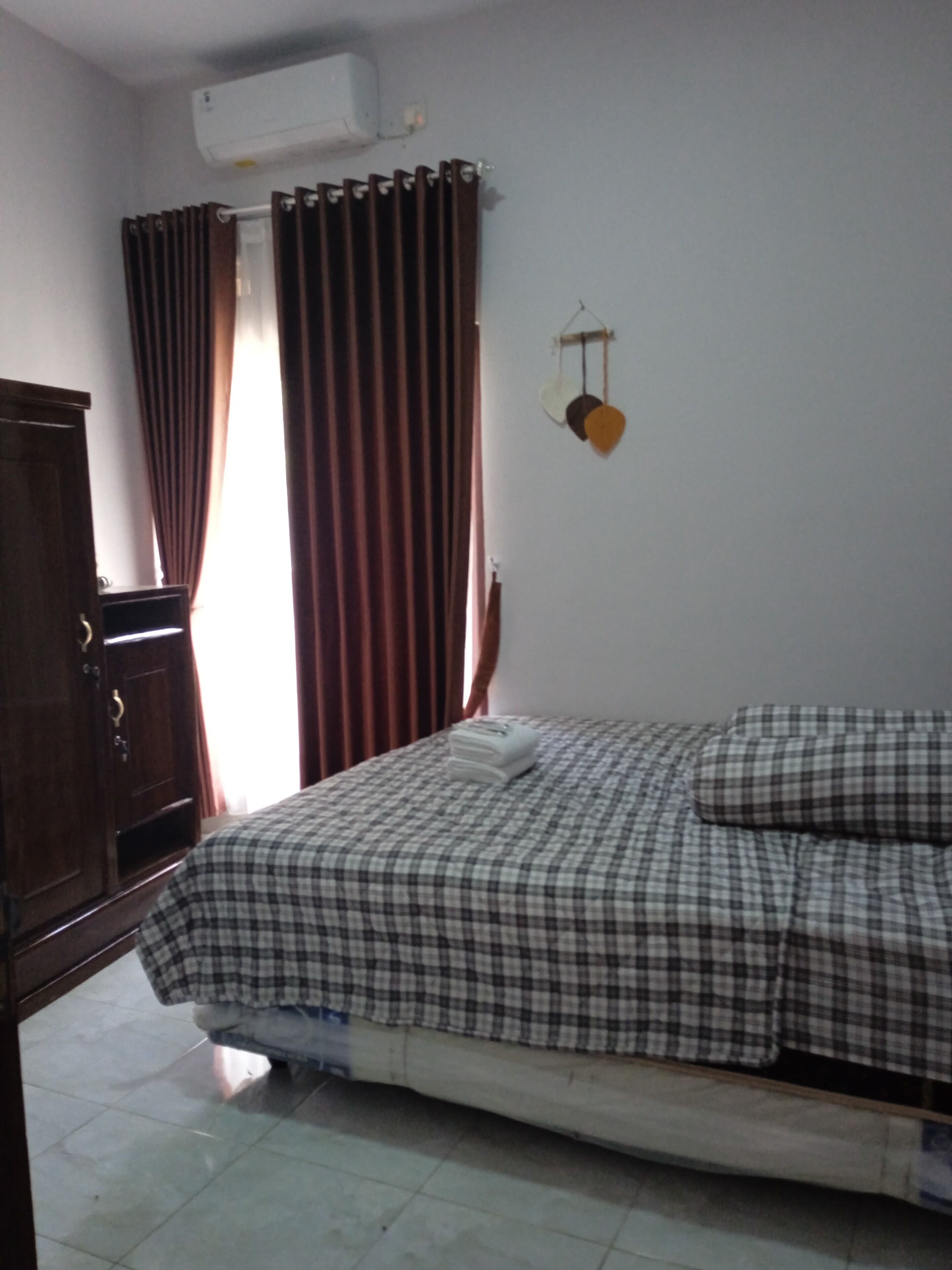 A bedroom with a bed, a wardrobe, a curtain, and a wall-mounted light fixture.