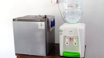 A small refrigerator and a water dispenser on a wooden table.